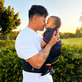 Load image into Gallery viewer, A father playing with his child who is comfortably seated in the HipSurfer Hip Seat Baby Carrier & Bum Bag. The child is enjoying the support and freedom provided by the carrier.