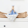 Load image into Gallery viewer, Peter Rabbit Comfort Blanket on wicker basket, highlighting its charming design and baby-safe materials.