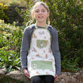 Load image into Gallery viewer, Children uses a charming gardening apron featuring Winnie the Pooh and friends' design. Made from 100% sustainably sourced cotton, it includes four green pockets, neck loop, and waist ties, suitable for children aged 6-11 years. Presented with a recycled belly band.