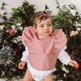 Load image into Gallery viewer, Primrose Snuggle Bib in a stylish design, featuring waterproof, easy-to-wipe material, an adjustable neck strap, and a handy pocket for catching spills.