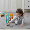 Load image into Gallery viewer, Child playing with one of the three cars included with the ramp in the same environment