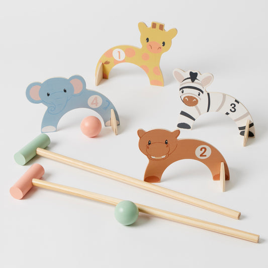 Toddlers playing with a wooden Animal Croquet Set featuring elephant, giraffe, hippo, and zebra hoops with wooden mallets.