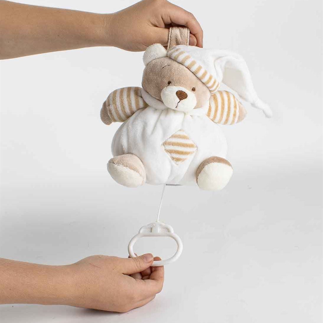 Person pulling the string on a Beige Musical Lullaby Bear, activating the soothing lullaby feature.