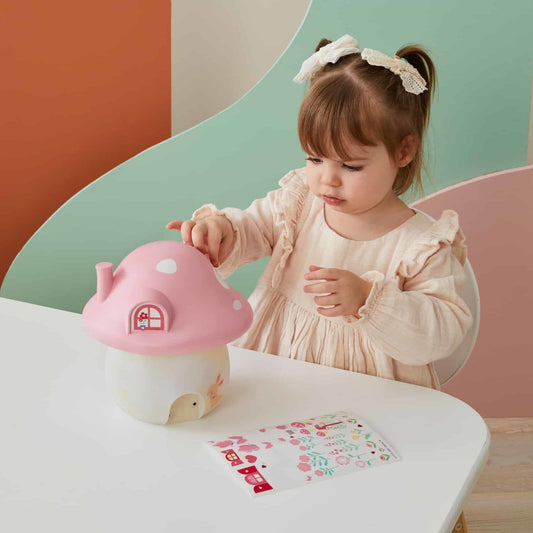 Little girl decorating the Mushroom Fairy House Night Light with stickers, personalizing it to her liking.