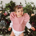 Load image into Gallery viewer, Primrose Snuggle Bib in a stylish design, featuring waterproof, easy-to-wipe material, an adjustable neck strap, and a handy pocket for catching spills.
