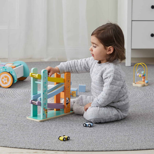 Child playing with the car ramp racer in a calm environment surrounded by toys