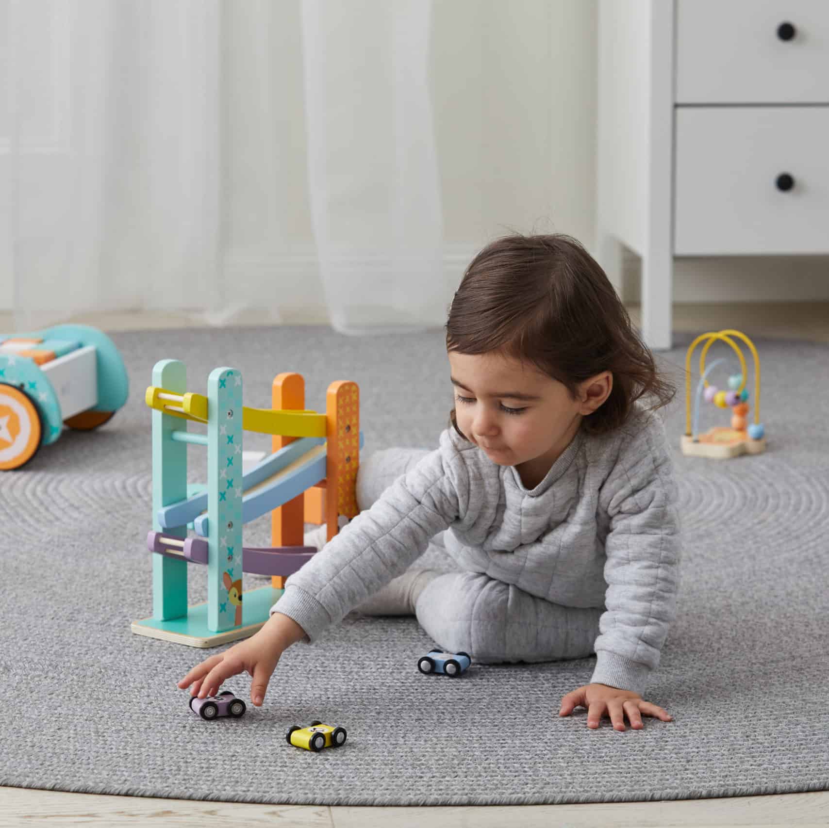 Child playing with one of the three cars included with the ramp in the same environment