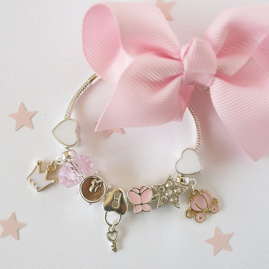 Cinderella Charm Bracelet by Lauren Hinkley in a gift box, featuring silver-plated charms including a glittering star, pink butterfly, and heart key charm